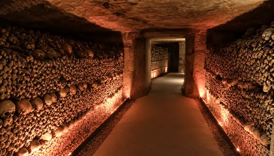 Galerie de l’ossuaire des Catacombes de Paris sous un éclairage rouge chaleureux