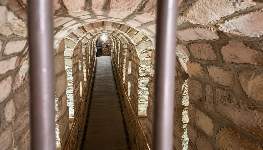 Passage étroit aux arches de pierre, vu derrière une grille